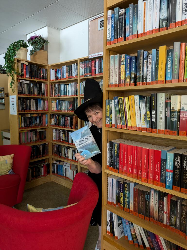 Bücherei Ebensee innen und Frau Rohrweck lugt hinter einem Regal hervor